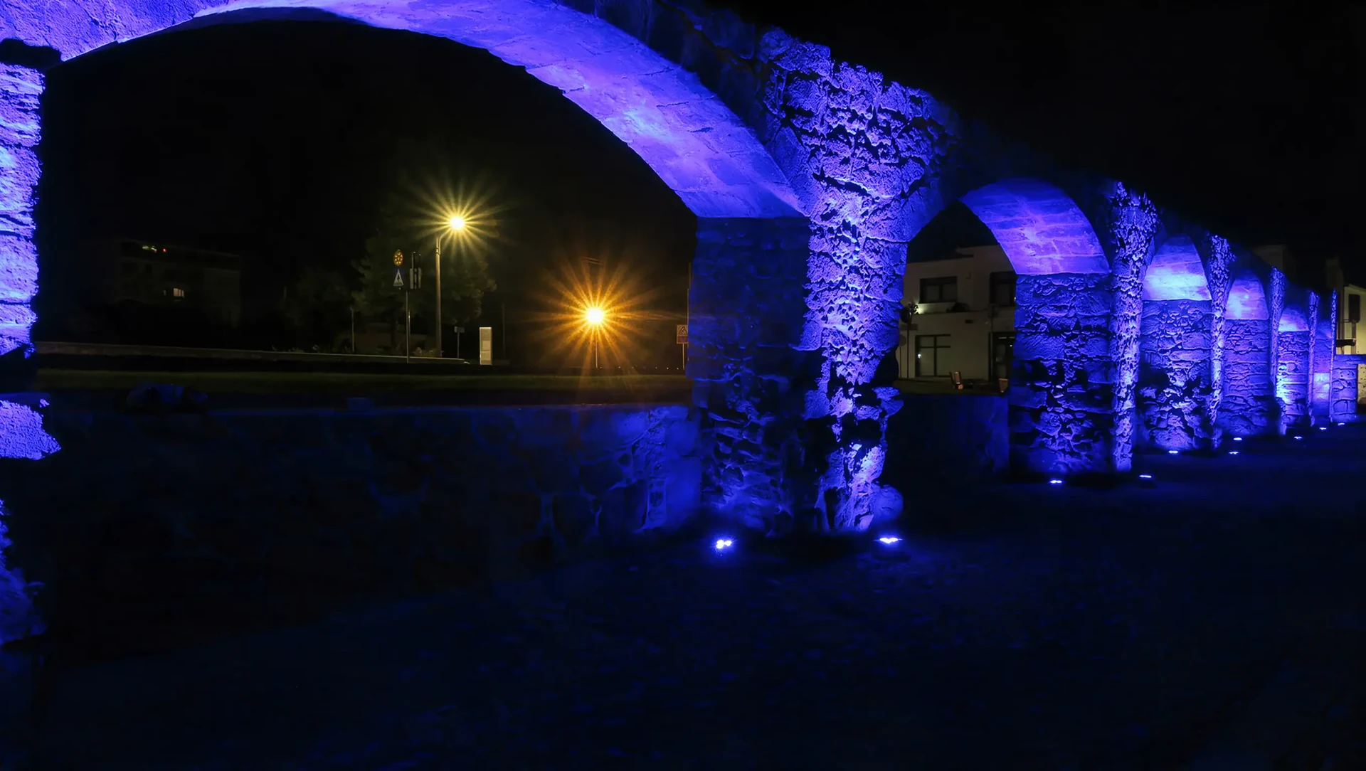 Stone arches illuminated in cool blue and violet light